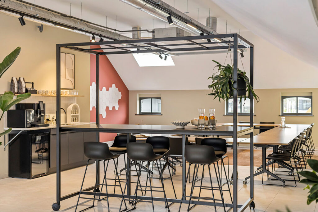 Ruime vergaderruimte met hoge bartafels en veel groen, een inspirerende plek voor brainstormsessies en zakelijke bijeenkomsten.