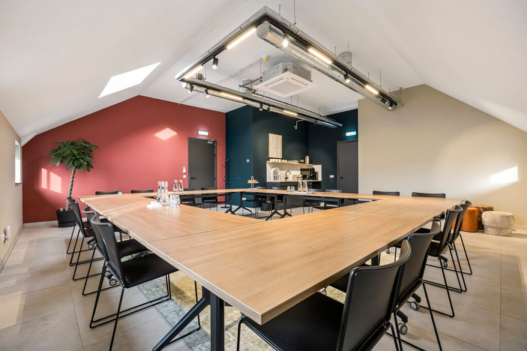Ruime vergaderruimte bij Onder de Pannen in Echt, met een U-vormige houten tafel, zwarte stoelen en een industriële uitstraling.