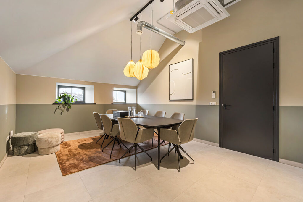 Ruime vergaderruimte bij Onder de Pannen in Echt, met een U-vormige houten tafel, zwarte stoelen en een industriële uitstraling.