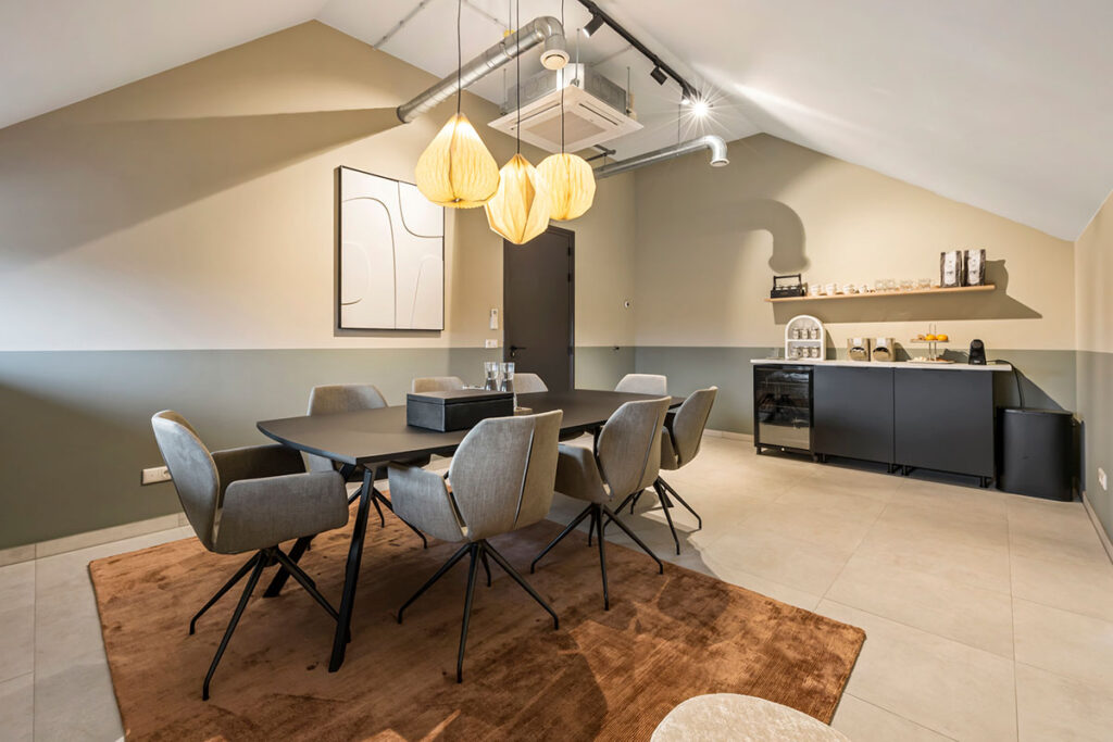 Ruime vergaderruimte bij Onder de Pannen in Echt, met een U-vormige houten tafel, zwarte stoelen en een industriële uitstraling.