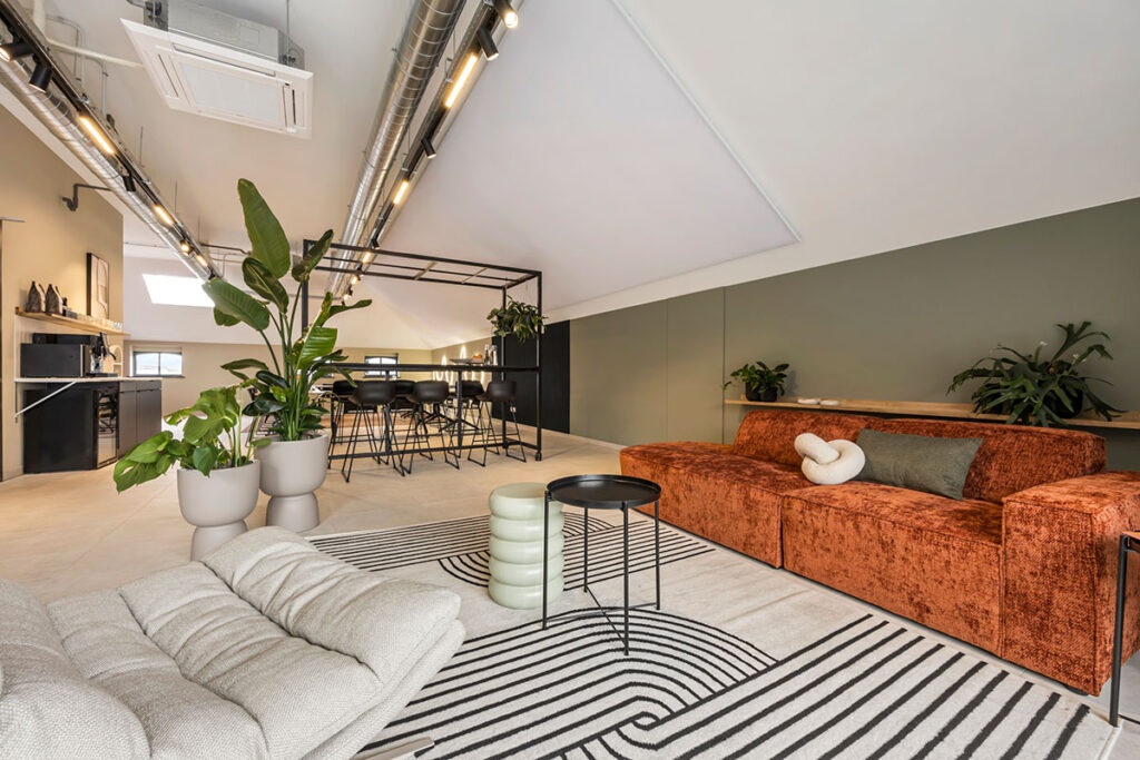 Ruime vergaderlocatie met een industriële look, voorzien van een U-vormige tafelopstelling, sfeerverlichting en moderne decoratie.