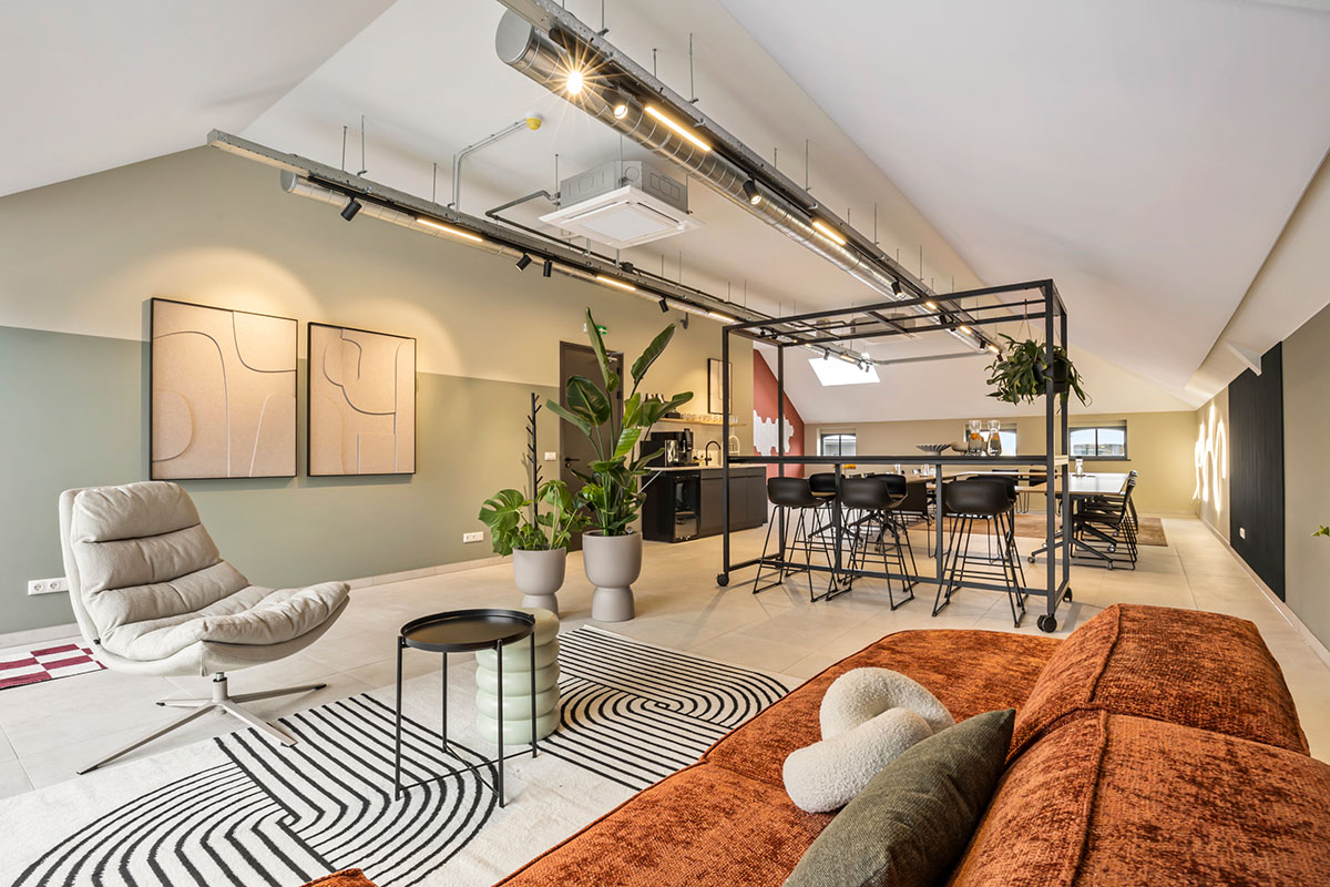 Gezellige loungehoek met een oranje fluwelen bank en een strak vormgegeven vergadertafel, ideaal voor een informele en productieve setting.