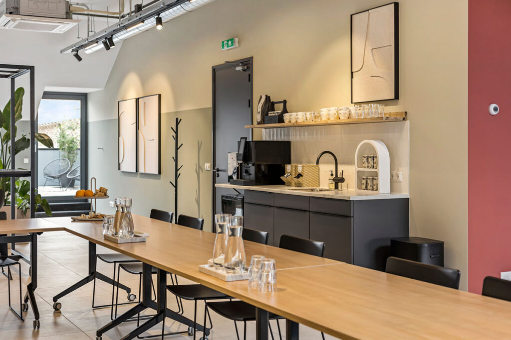 Stijlvolle vergaderruimte bij Onder de Pannen in Echt, met een open koffiecorner, moderne kunst aan de muur en een warme, uitnodigende sfeer.